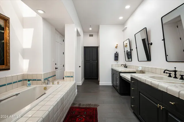 a spacious bathroom with a bathtub sink double vanity and mirror