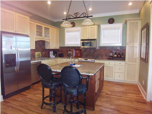 10140 Co Hwy Inlet Beach, Unit 33 30A Inlet Beach, FL 32461 - Photo 3 of 13 a kitchen with stainless steel appliances granite countertop a sink a stove a refrigerator cabinets and dining table