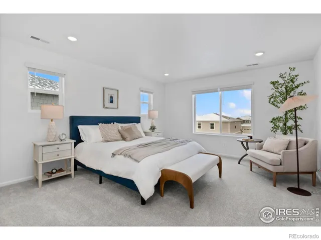 a spacious bedroom with a bed a couch and potted plant on the dresser
