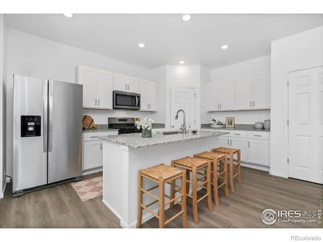 a kitchen with stainless steel appliances white cabinets and wooden floor