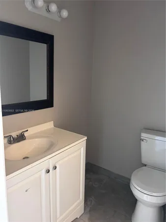 a bathroom with a toilet sink vanity and mirror