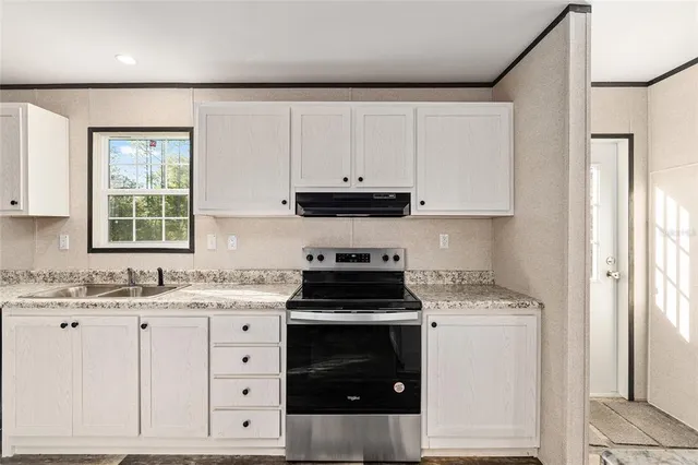 a kitchen with granite countertop white cabinets and black appliances