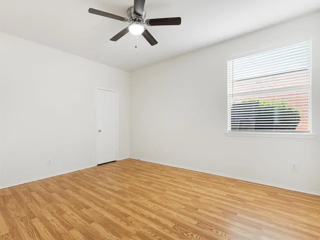 an empty room with a window and a ceiling fan