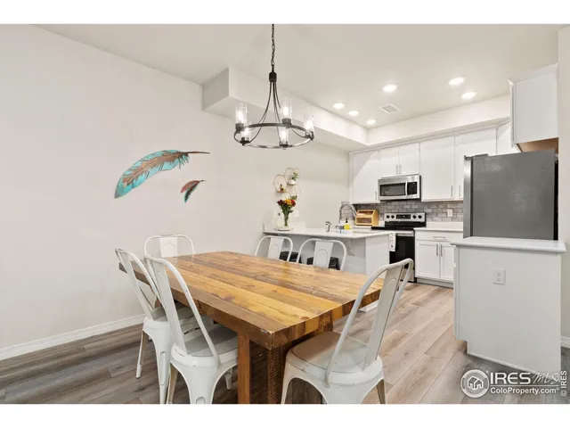 a kitchen with stainless steel appliances kitchen island granite countertop a table chairs and a refrigerator