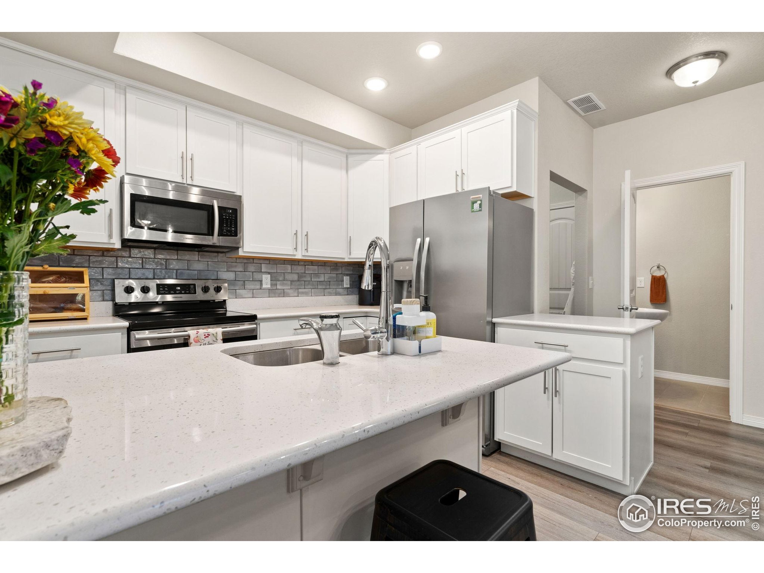 865 Winding Brook Drive Berthoud, CO 80513 - Photo 9 of 27 a kitchen with stainless steel appliances a sink a microwave a refrigerator and cabinets