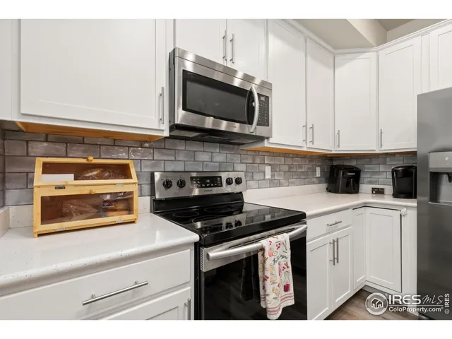 a kitchen with stainless steel appliances granite countertop white cabinets and black stove top oven with granite countertops