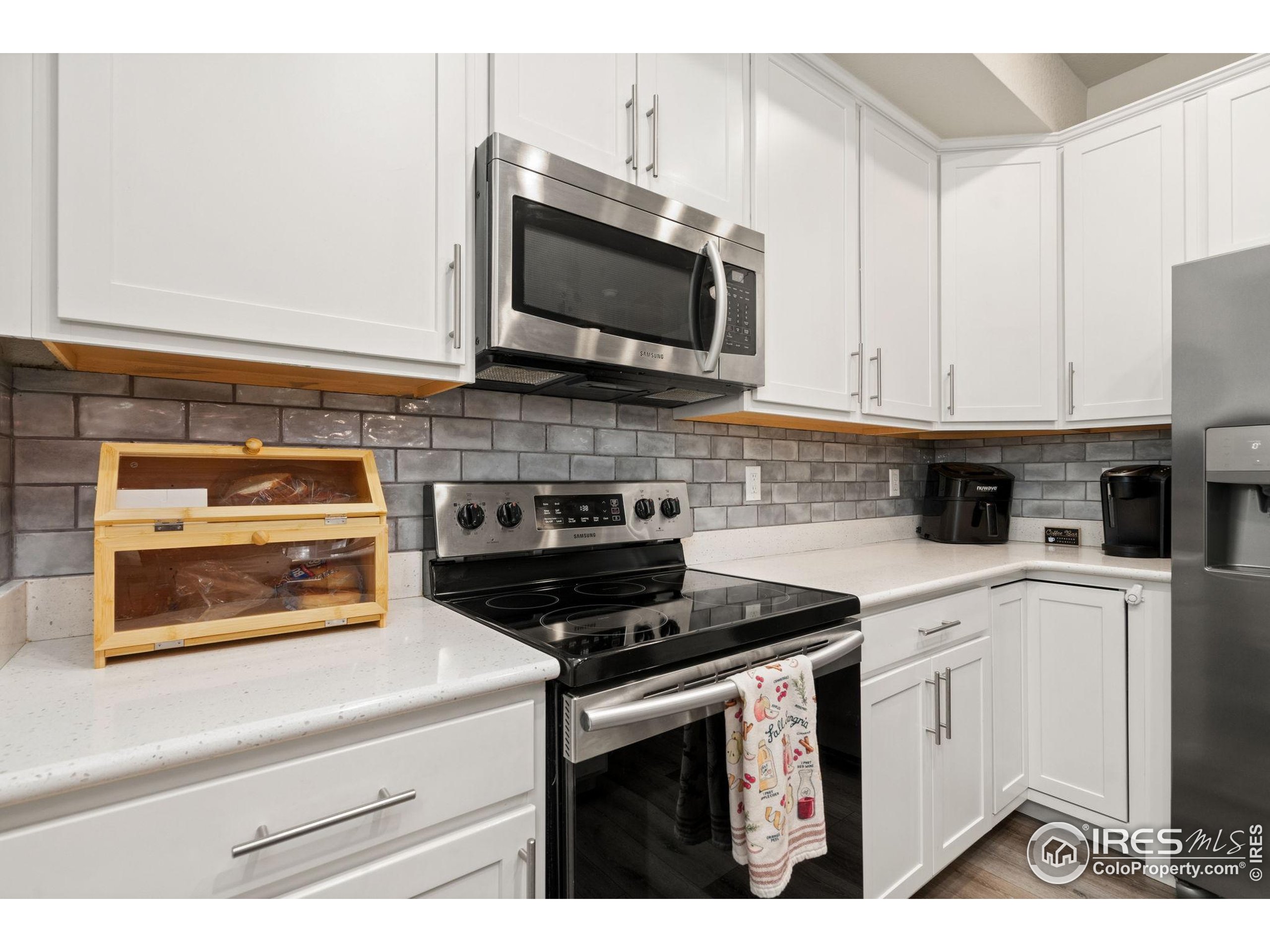 865 Winding Brook Drive Berthoud, CO 80513 - Photo 10 of 27 a kitchen with stainless steel appliances granite countertop white cabinets and black stove top oven with granite countertops