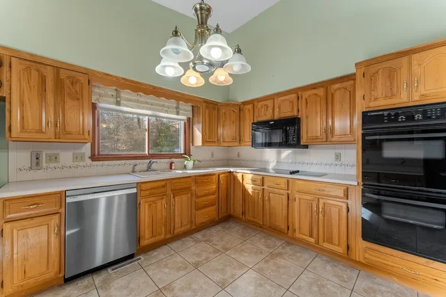 a large kitchen with stainless steel appliances granite countertop a stove top oven a sink dishwasher and wooden cabinets