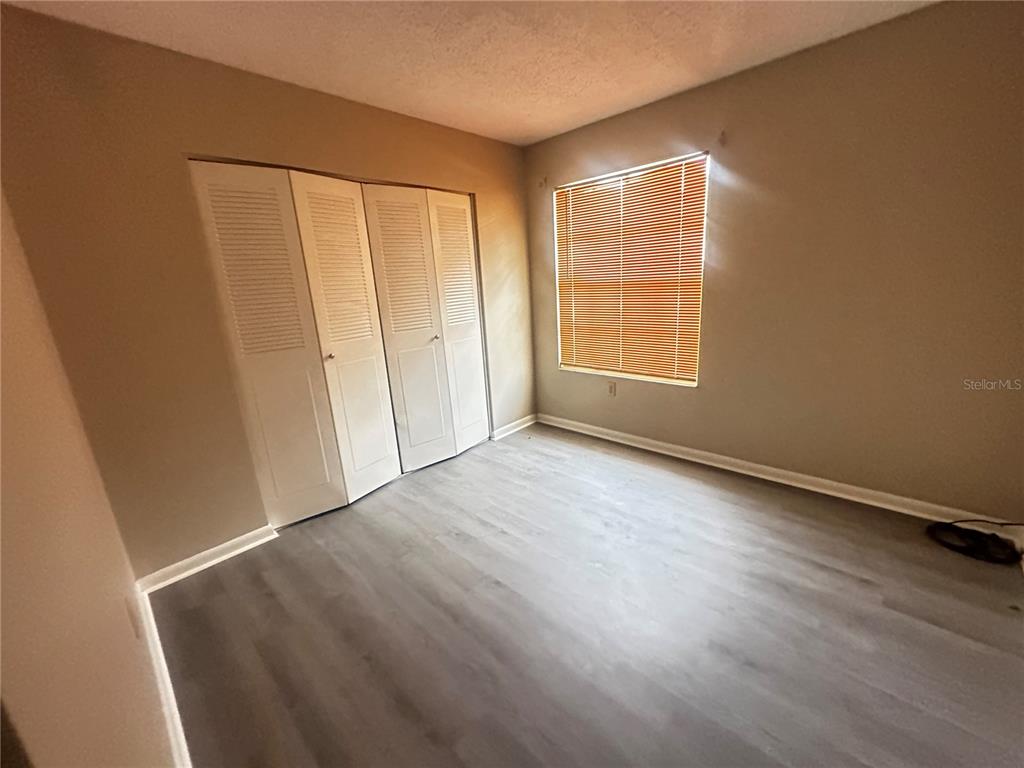 66 Silver Lane Ocala, FL 34472 - Photo 4 of 10 an empty room with wooden floor and windows with curtains