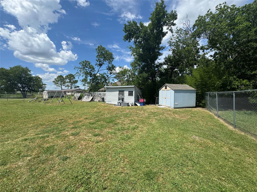 207 College Mound Road Terrell, TX 75160 - Photo 14 of 14 Expansive grassy yard with a chain-link fence, offering two utility sheds for storage