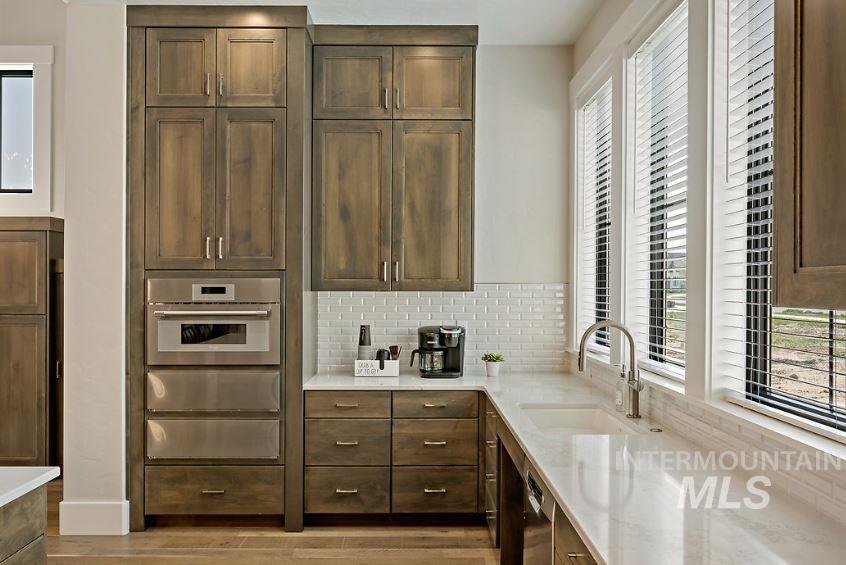 3480 East Macumbo Lane Meridian, ID 83642 - Photo 35 of 43 Kitchen with healthy amount of natural light, light stone countertops, tasteful backsplash, and dark brown cabinetry
