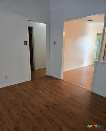 an empty room with wooden floor and mirror