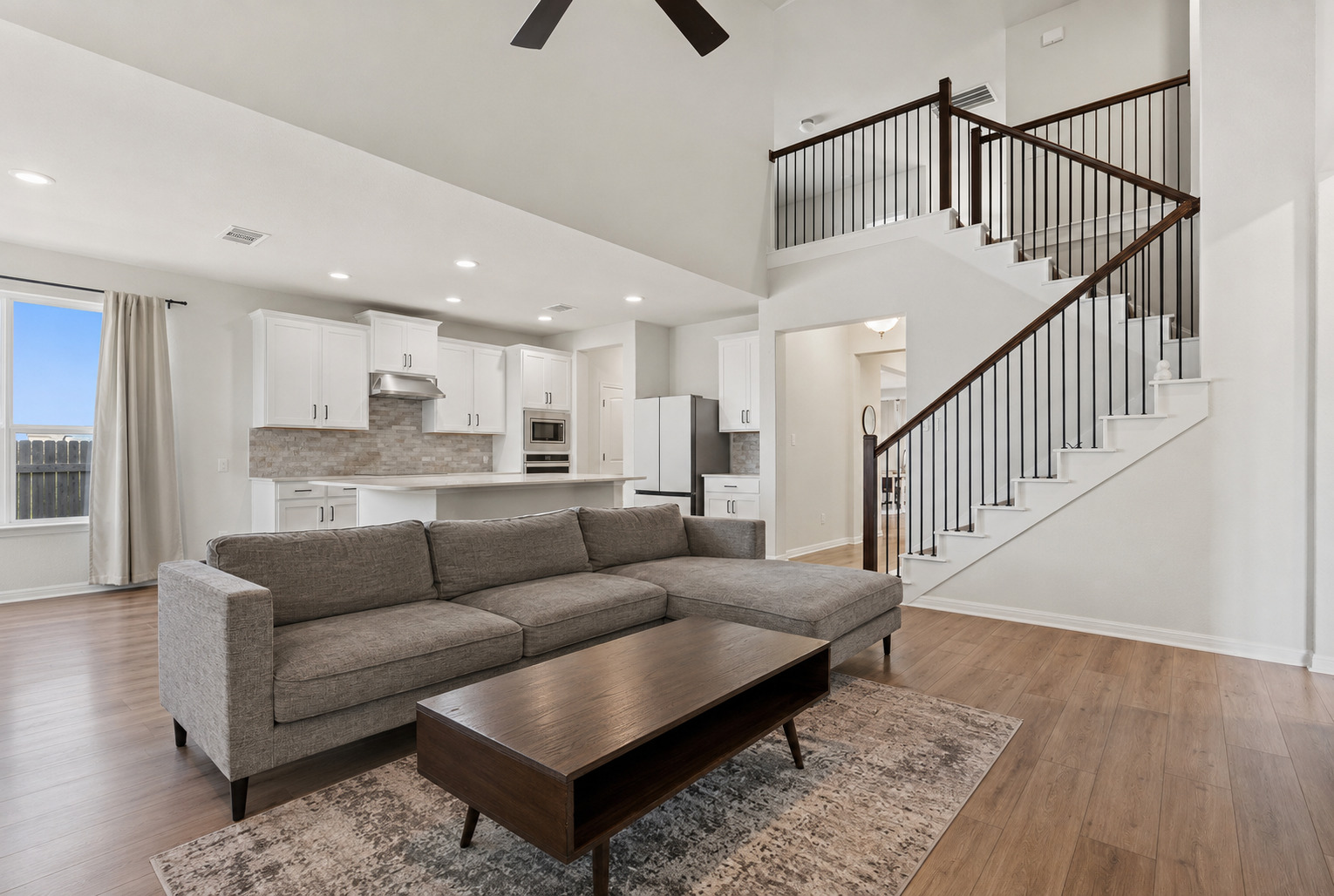 100 Panico Road Hutto, TX 78634 - Photo 12 of 28 A vast living area features high ceilings, an open-concept kitchen, and a striking staircase.