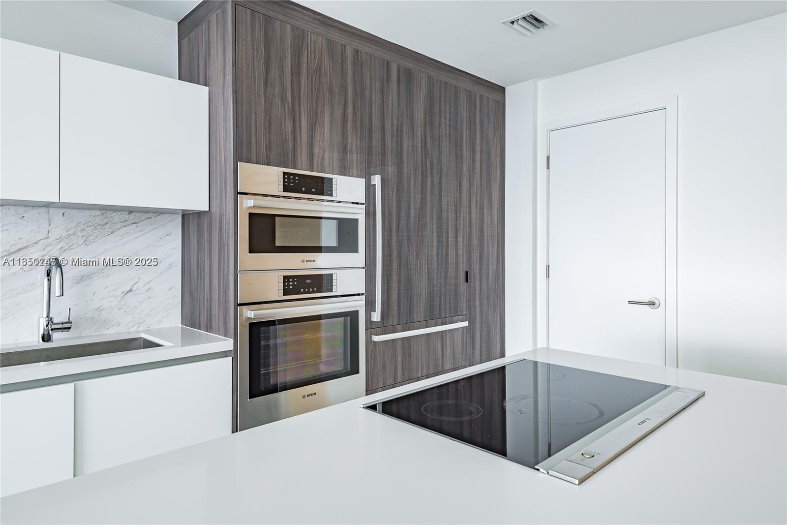 851 Northeast 1st Avenue, Unit 2100 Miami, FL 33132 - Photo 5 of 40 a kitchen with granite countertop a sink and a stove