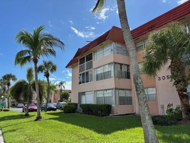 a front view of multi story residential apartment building with yard and green space