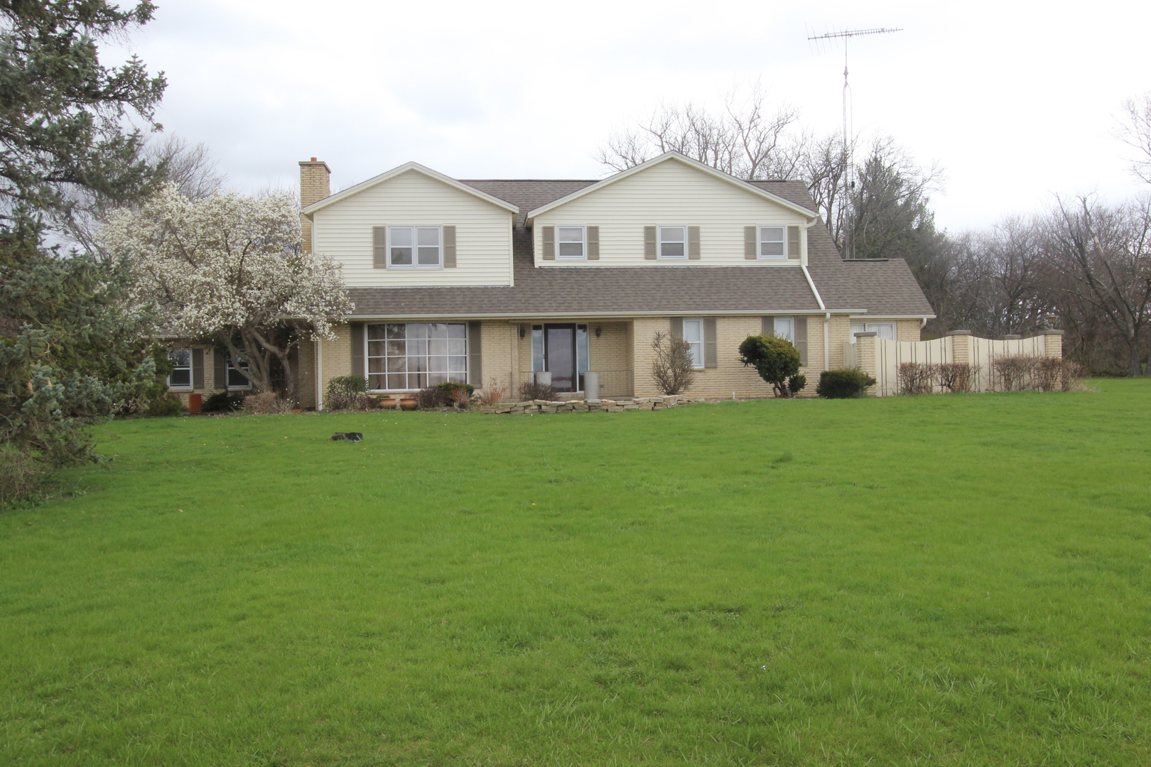 a front view of a house with a garden and trees