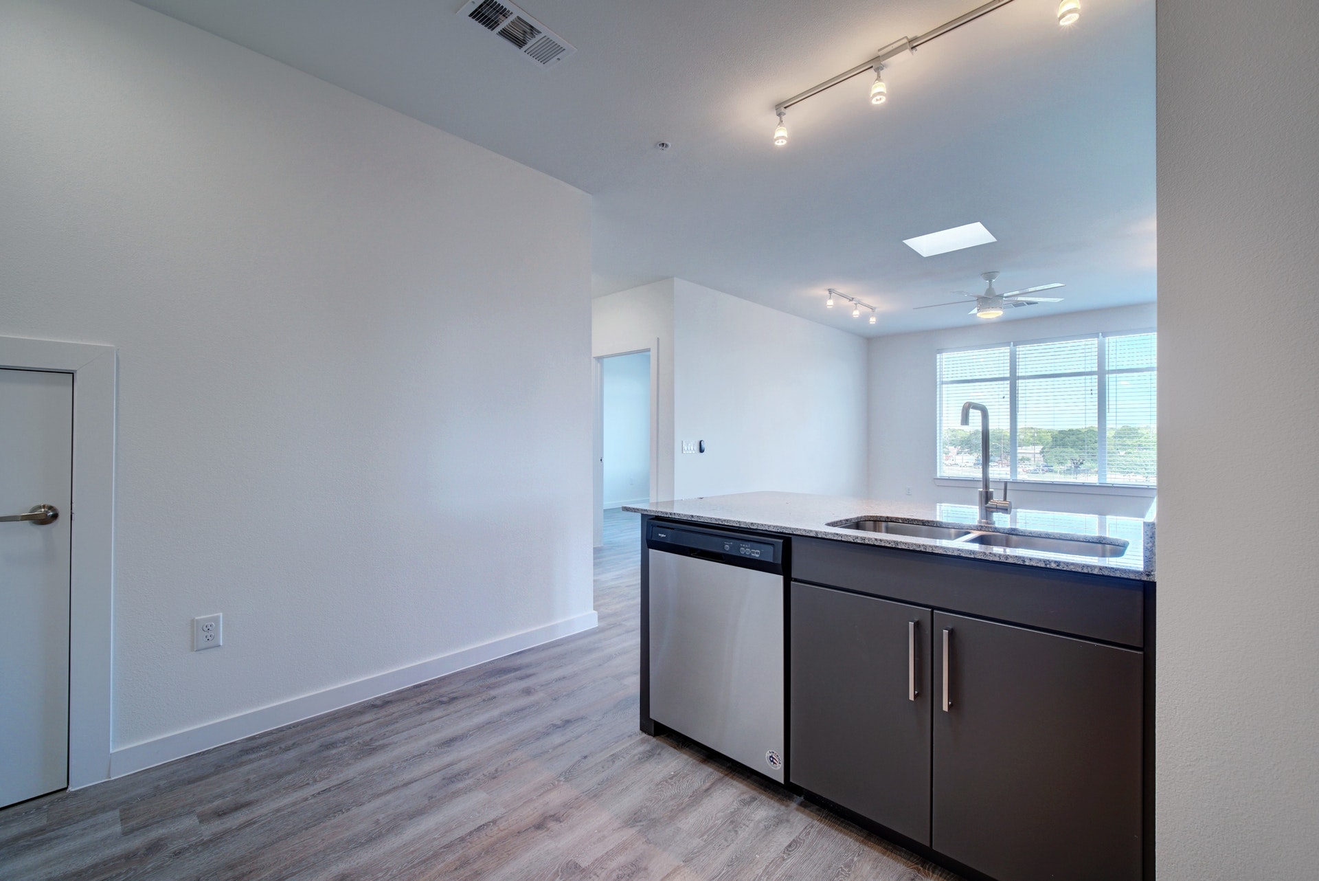 13130 Pond Springs Road, Unit 2203 Austin, TX 78729 - Photo 13 of 32 Kitchen featuring track lighting, dishwasher, light wood-type flooring, light stone countertops, and a ceiling fan