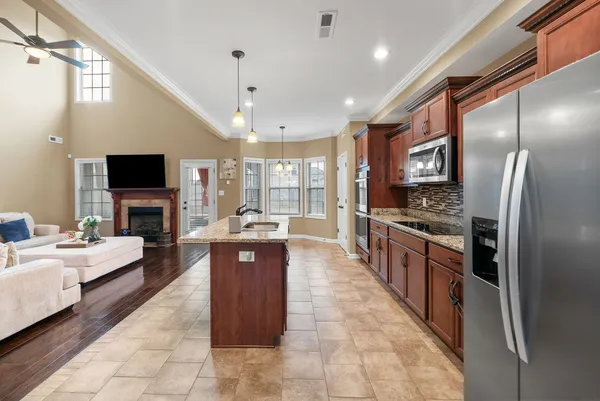 a large kitchen with stainless steel appliances granite countertop a large counter top a stove a chimney a sink and a refrigerator
