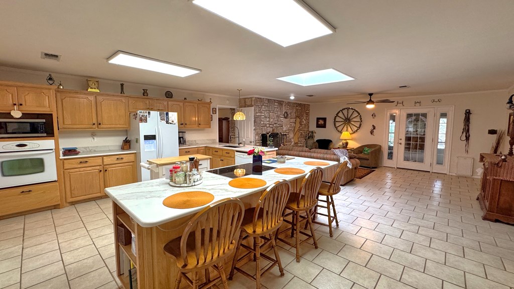 305 Rock Ridge Kerrville, TX 78028 - Photo 4 of 36 a dining hall with stainless steel appliances kitchen island granite countertop a table chairs and a refrigerator
