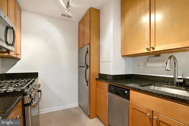 a kitchen with granite countertop a sink a stove and refrigerator