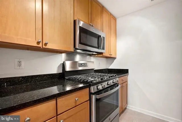 a kitchen with stainless steel appliances granite countertop a stove a microwave and a sink