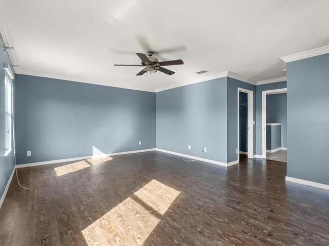 a view of a big room with wooden floor and a ceiling fan