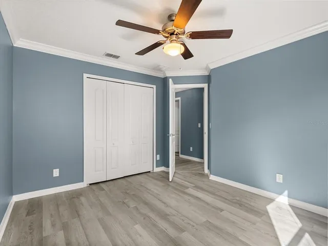 wooden floor in an empty room with a chandelier fan