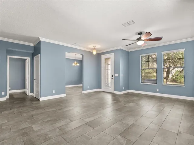a view of an empty room with window and chandelier fan
