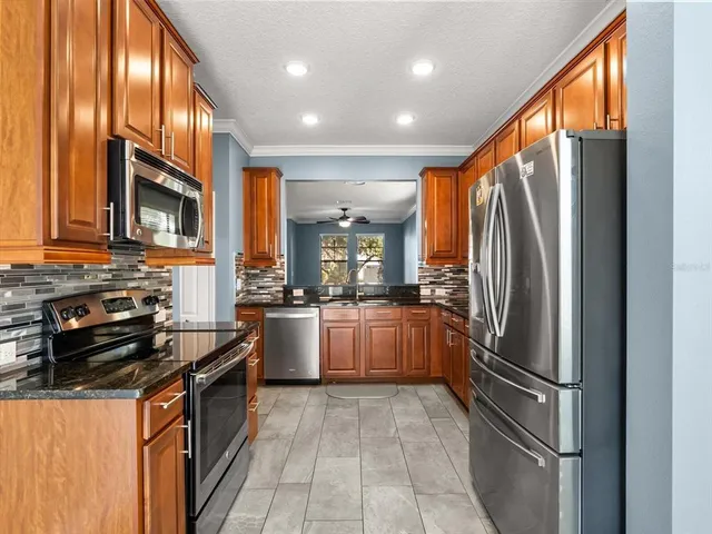 a kitchen with stainless steel appliances granite countertop a refrigerator a stove and a sink