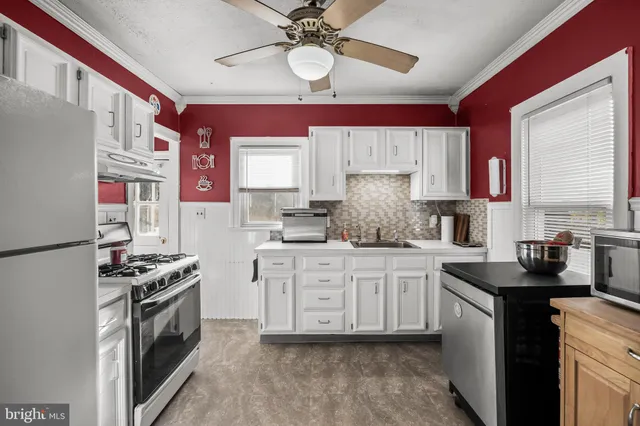 a kitchen with stainless steel appliances granite countertop a sink a stove a refrigerator and island with wooden floor