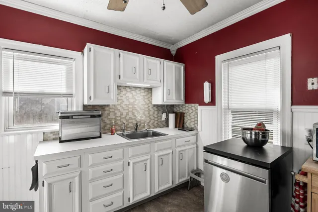 a kitchen with white cabinets and window