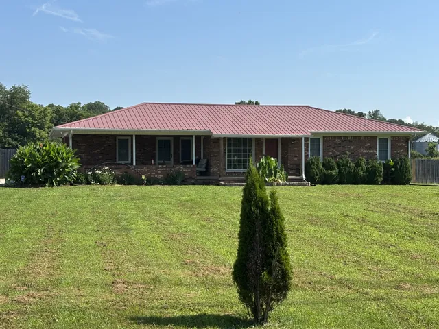 a front view of a house with a garden and trees
