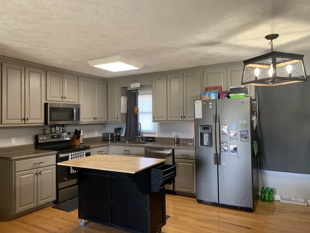 a kitchen with stainless steel appliances granite countertop a refrigerator a stove a sink and a microwave