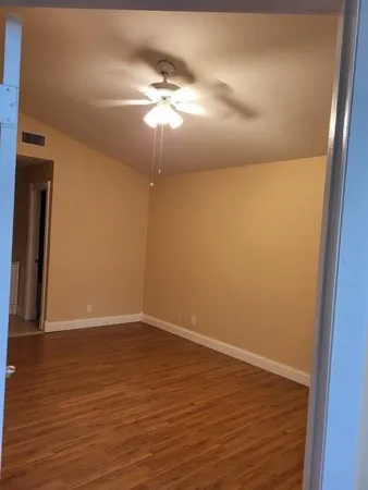 an empty room with wooden floor chandelier fan and closet area