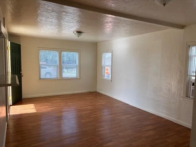 an empty room with wooden floor cabinet and windows