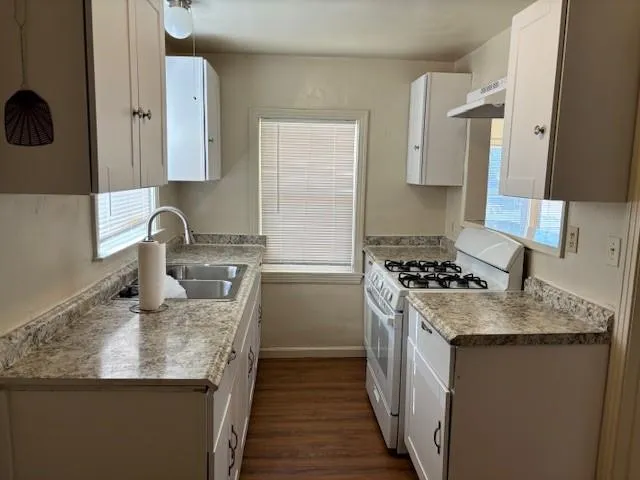 a kitchen with granite countertop a sink stove and refrigerator