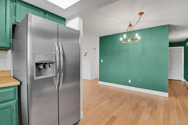 a view of a kitchen with a fridge and wooden floor
