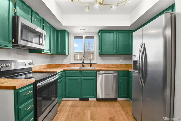 a kitchen with stainless steel appliances granite countertop a refrigerator a sink dishwasher a washer and dryer with wooden cabinets