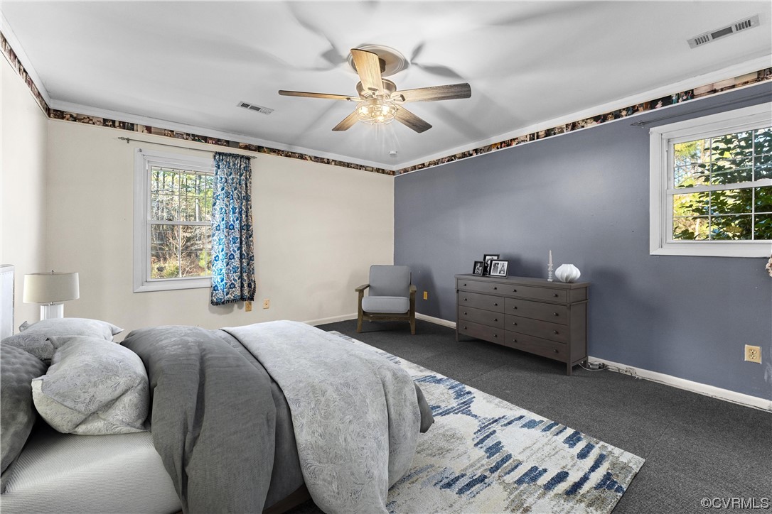 10083 Burkes Pond Road North, VA 23128 - Photo 23 of 36 a spacious bedroom with a bed and a chandelier