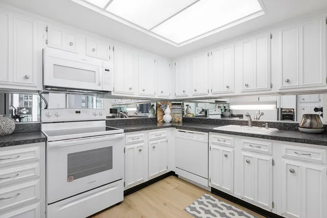 a kitchen with granite countertop white cabinets and white appliances