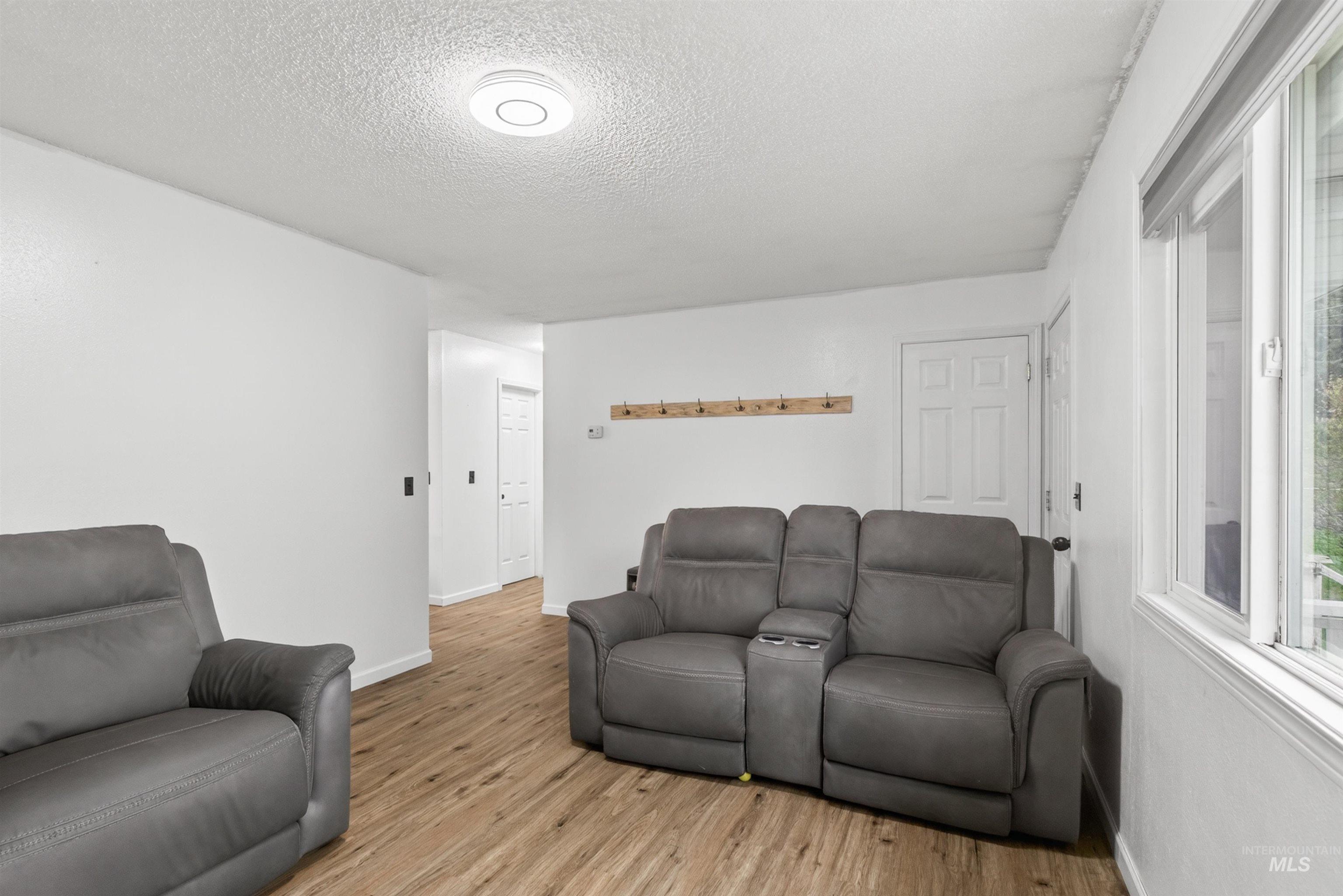 247 North Beech Street Genesee, ID 83832 - Photo 11 of 27 Living area featuring wood-finish flooring, white painted walls, and a ceiling-mounted light fixture