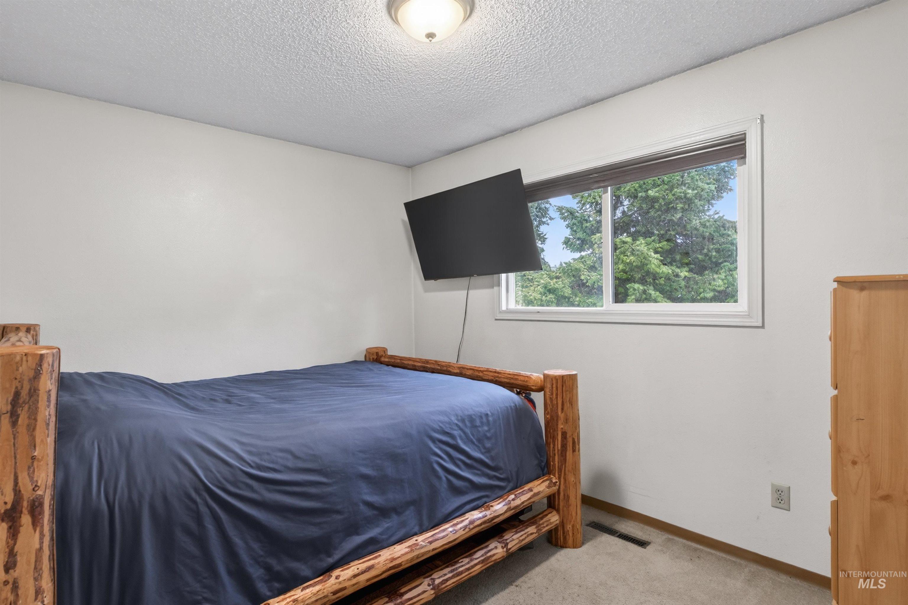 247 North Beech Street Genesee, ID 83832 - Photo 13 of 27 Bright room featuring a window with exterior tree scenery, soft neutral wall paint, and a textured ceiling