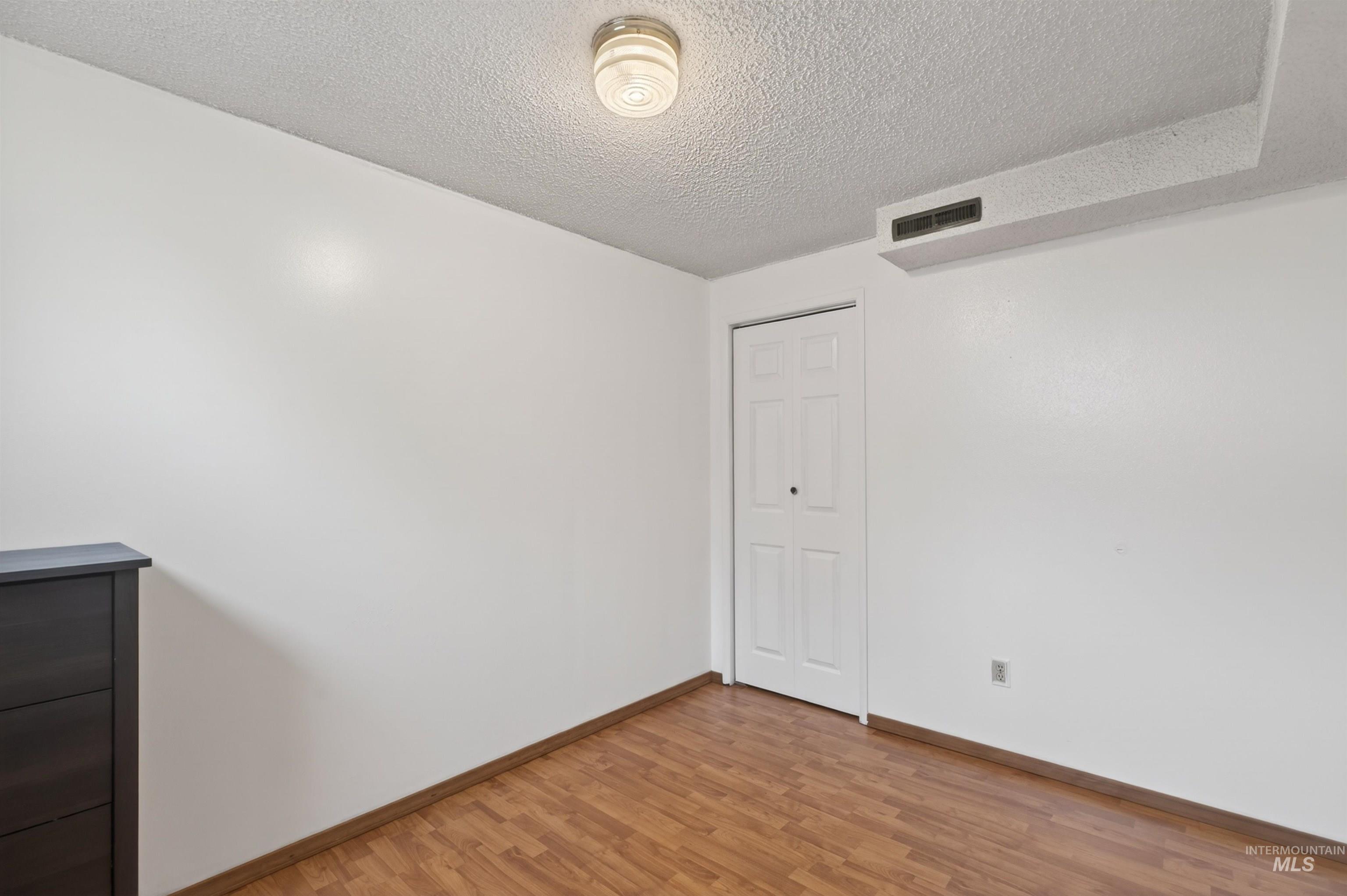 247 North Beech Street Genesee, ID 83832 - Photo 19 of 27 Room featuring wood-finish flooring, a bi-fold closet door, and a ceiling-mounted light fixture