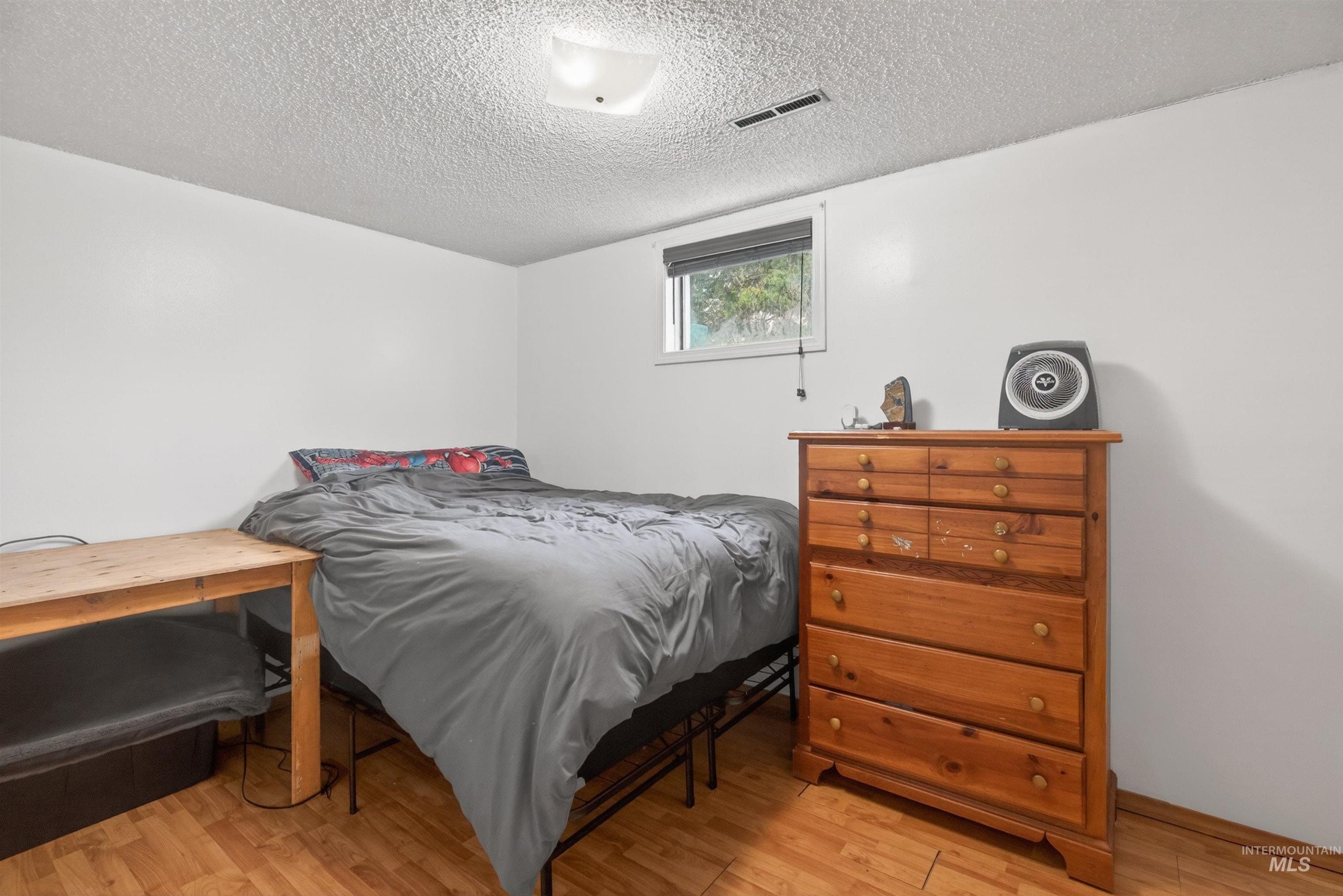 247 North Beech Street Genesee, ID 83832 - Photo 20 of 27 White-painted room featuring wood-finish flooring, a ceiling-mounted light fixture, and a window with blinds