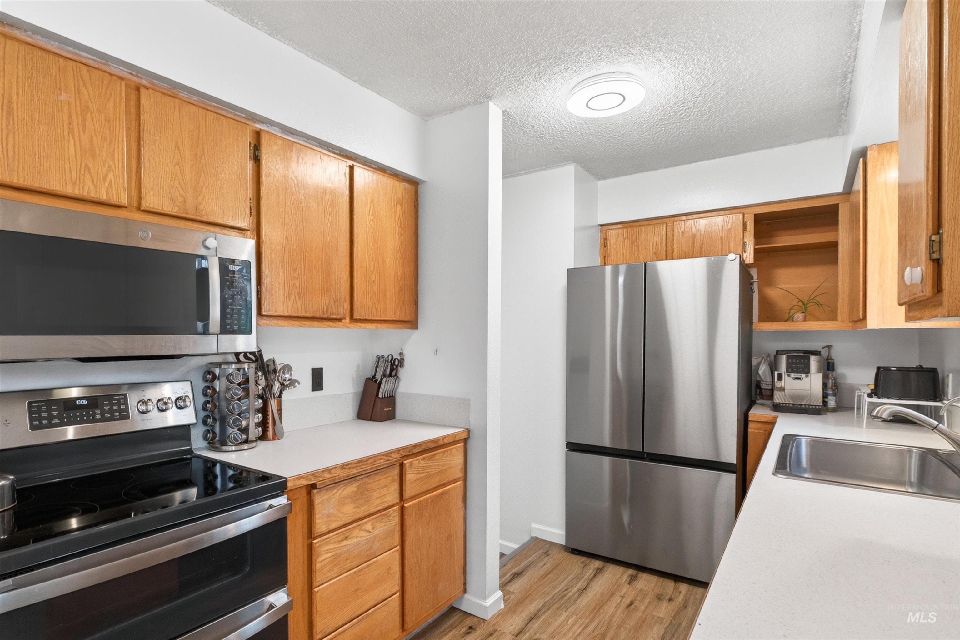 247 North Beech Street Genesee, ID 83832 - Photo 7 of 27 Kitchen featuring wood cabinetry, stainless steel appliances, white countertops, and wood-finish flooring