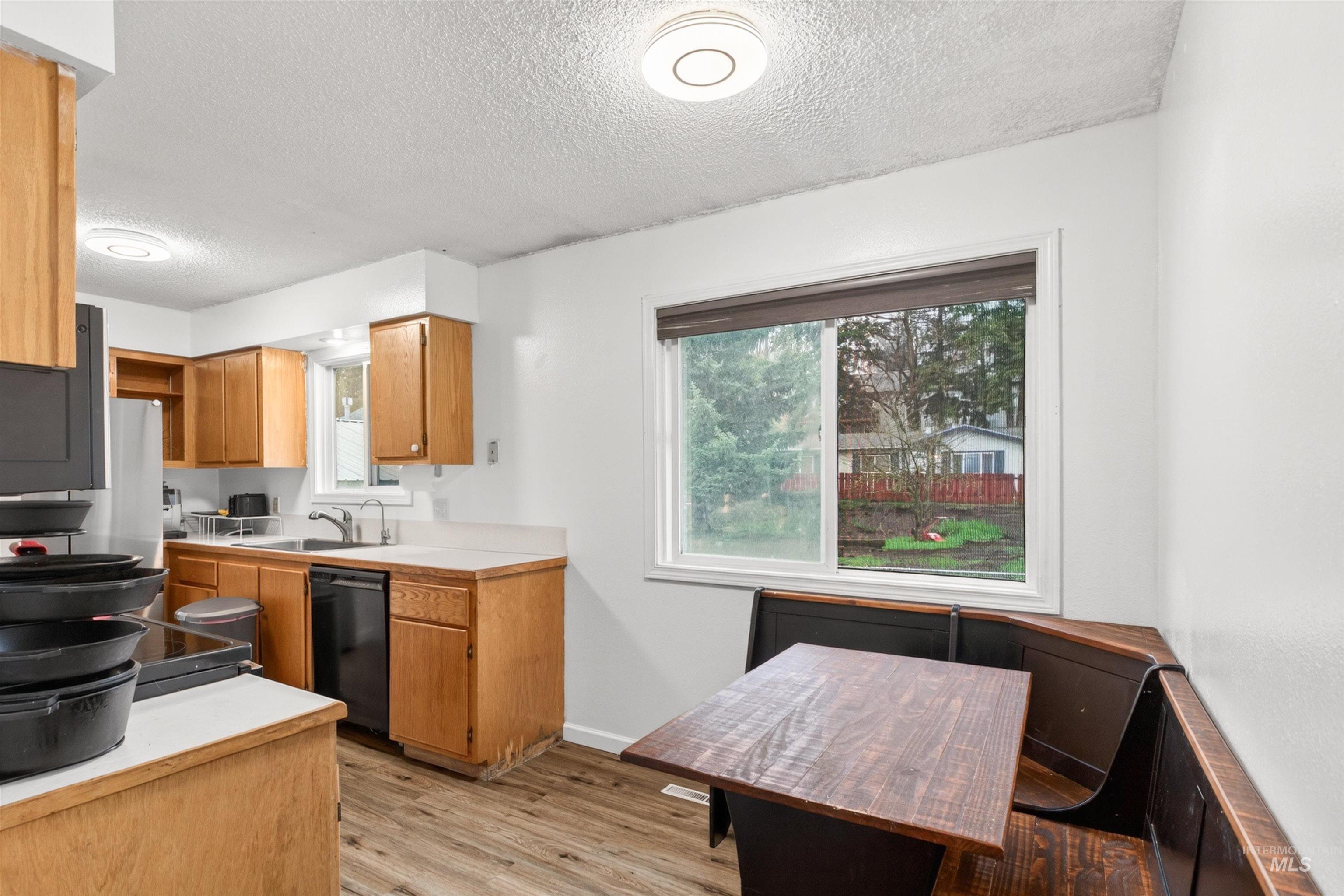 247 North Beech Street Genesee, ID 83832 - Photo 10 of 27 Functional kitchen featuring wood-finish cabinetry, light-toned countertops, and a built-in banquette dining area with a wood-finish tabletop