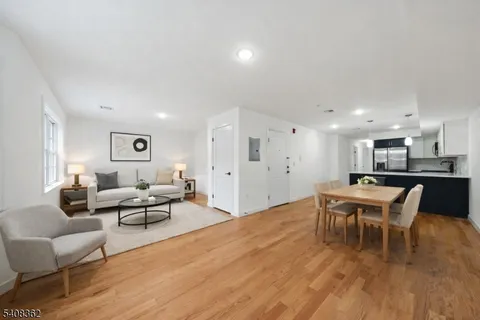 a living room with furniture wooden floor and a kitchen view