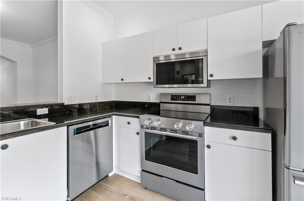 3281 Lindsey Lane, Unit 55 Naples, FL 34109 - Photo 2 of 43 a kitchen with granite countertop a sink dishwasher a stove and a refrigerator with cabinets