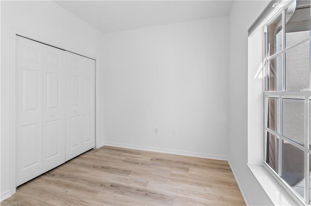 3281 Lindsey Lane, Unit 55 Naples, FL 34109 - Photo 23 of 43 a view of an empty room with wooden floor and a window