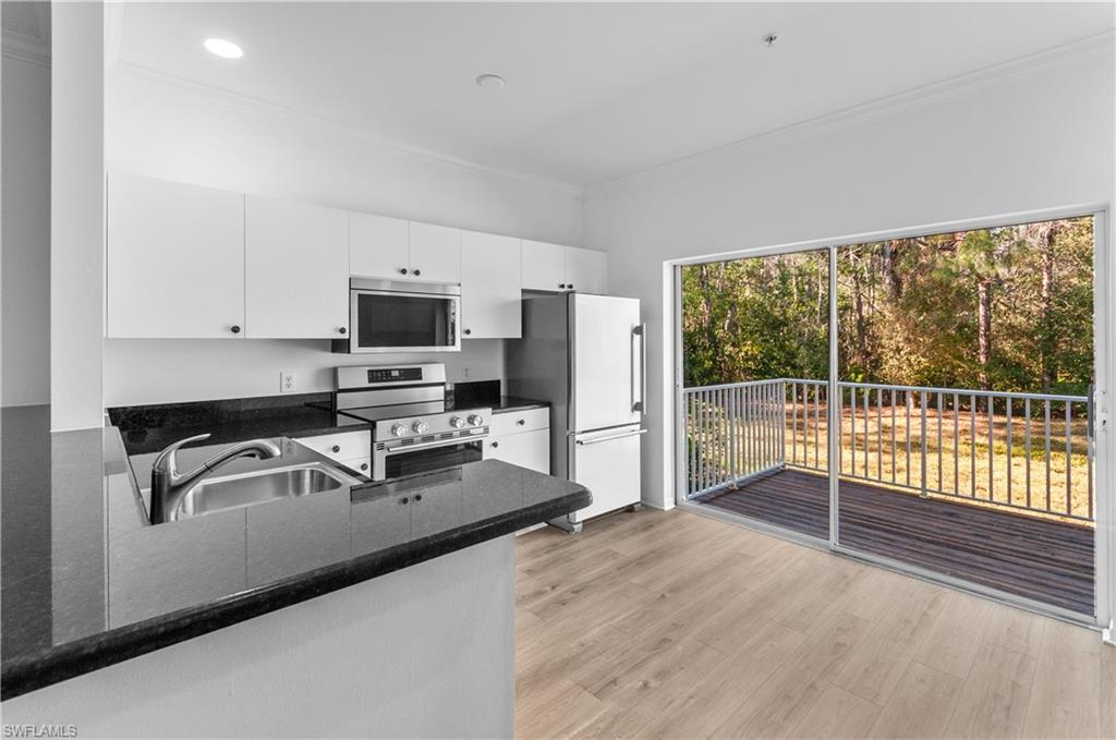 3281 Lindsey Lane, Unit 55 Naples, FL 34109 - Photo 3 of 43 a kitchen with granite countertop a stove a sink and a microwave